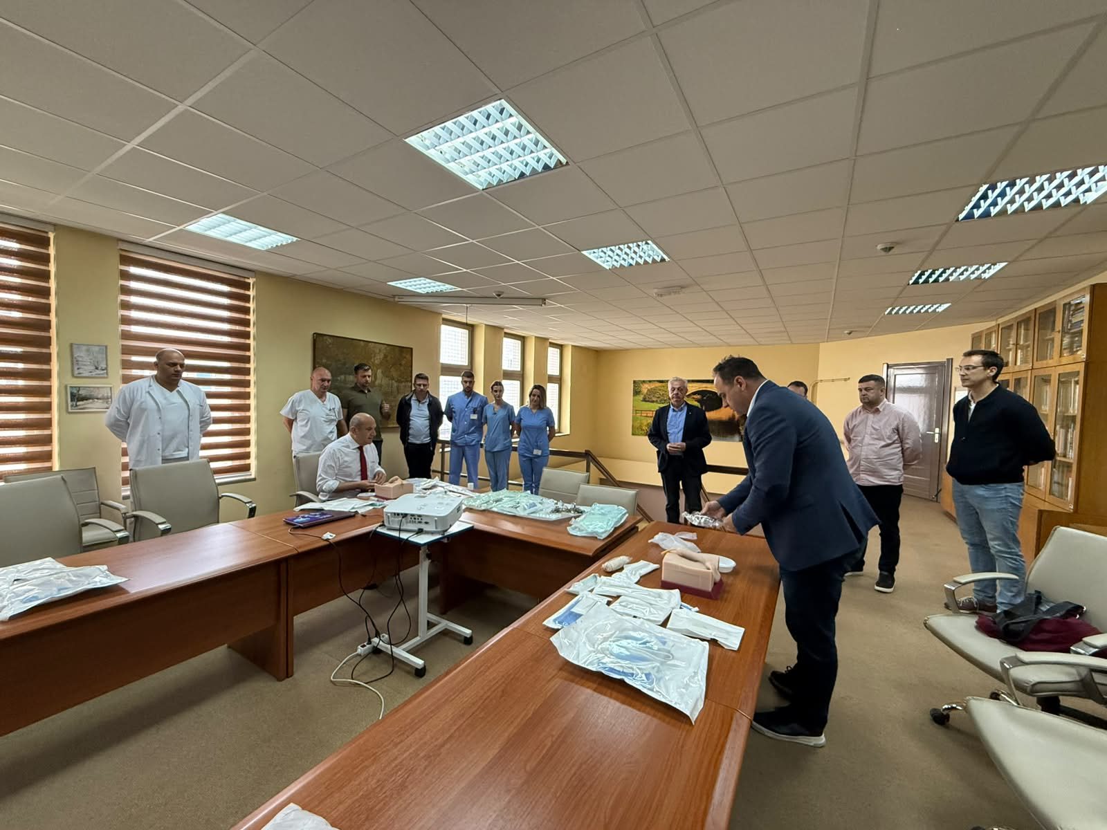 Učesnici kursa okupljeni oko stola sa hirurškim instrumentima i modelima za vježbu